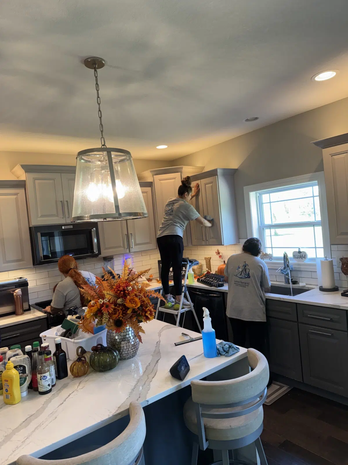 Three cleaners wiping cabinets and counters in a residential kitchen — Leskuin Cleaning LLC in Springfield